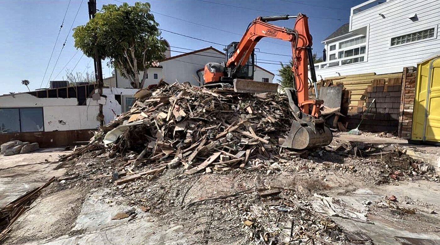 A2Z excavator piling debris from a residential teardown